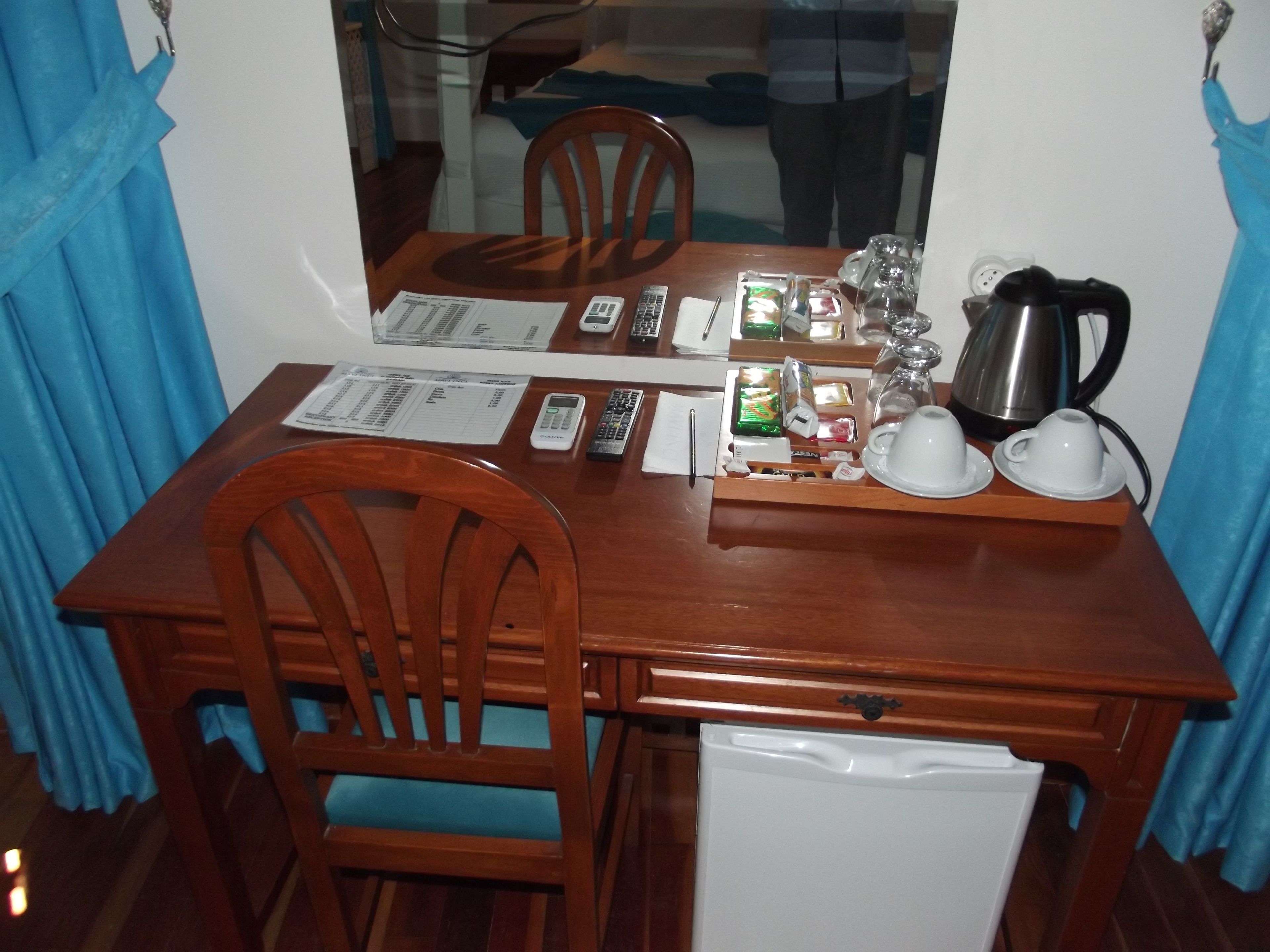 A wooden dining table with chairs, a mirror, and various items including a kettle, cups, and a tray.