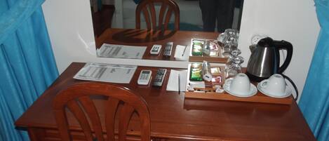 A wooden dining table with chairs, a mirror, and various items including a kettle, cups, and a tray.