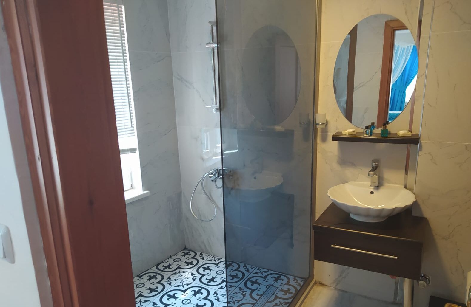 A bathroom with a glass-enclosed shower, a white sink, and a mirror above it.