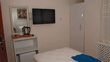 A bedroom with a bed, a TV, a wardrobe, a small kitchenette, and a mirror.