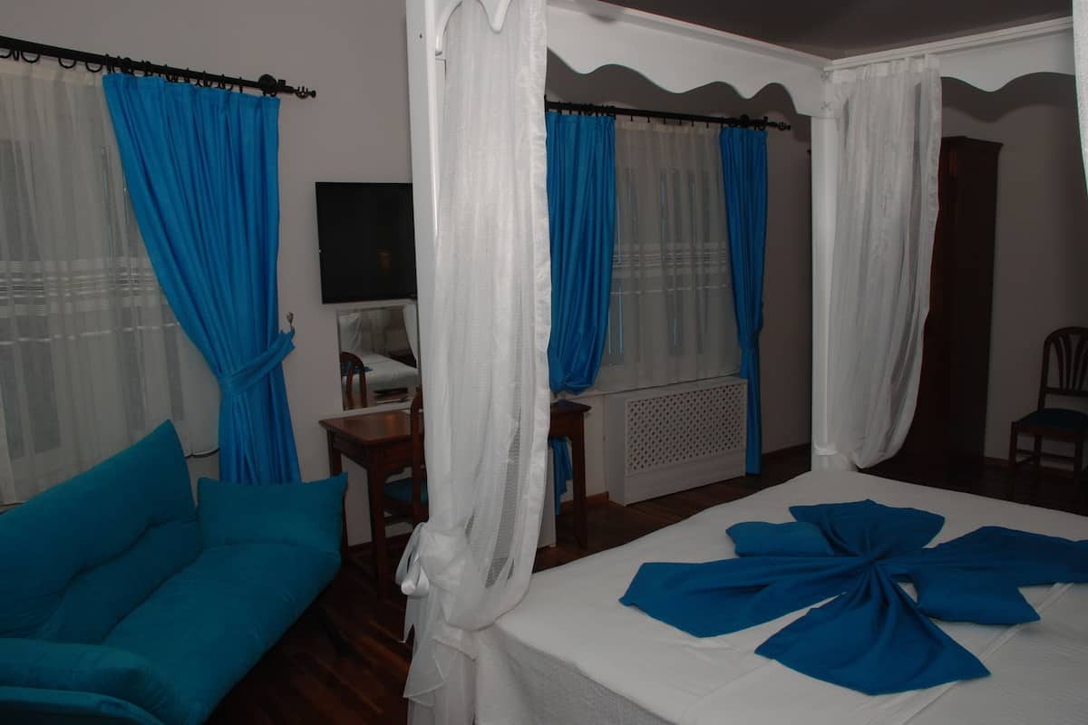 A bedroom with a bed, a chair, a table, and curtains.