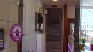 Rebedor d'hotel amb una escala, un rellotge i una recepció.