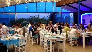 Un restaurant amb diverses taules i caires, grans finestres i vista a l'exterior.