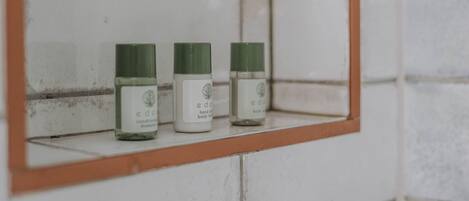 Three bottles of 'e' body lotion on a white tiled shelf.