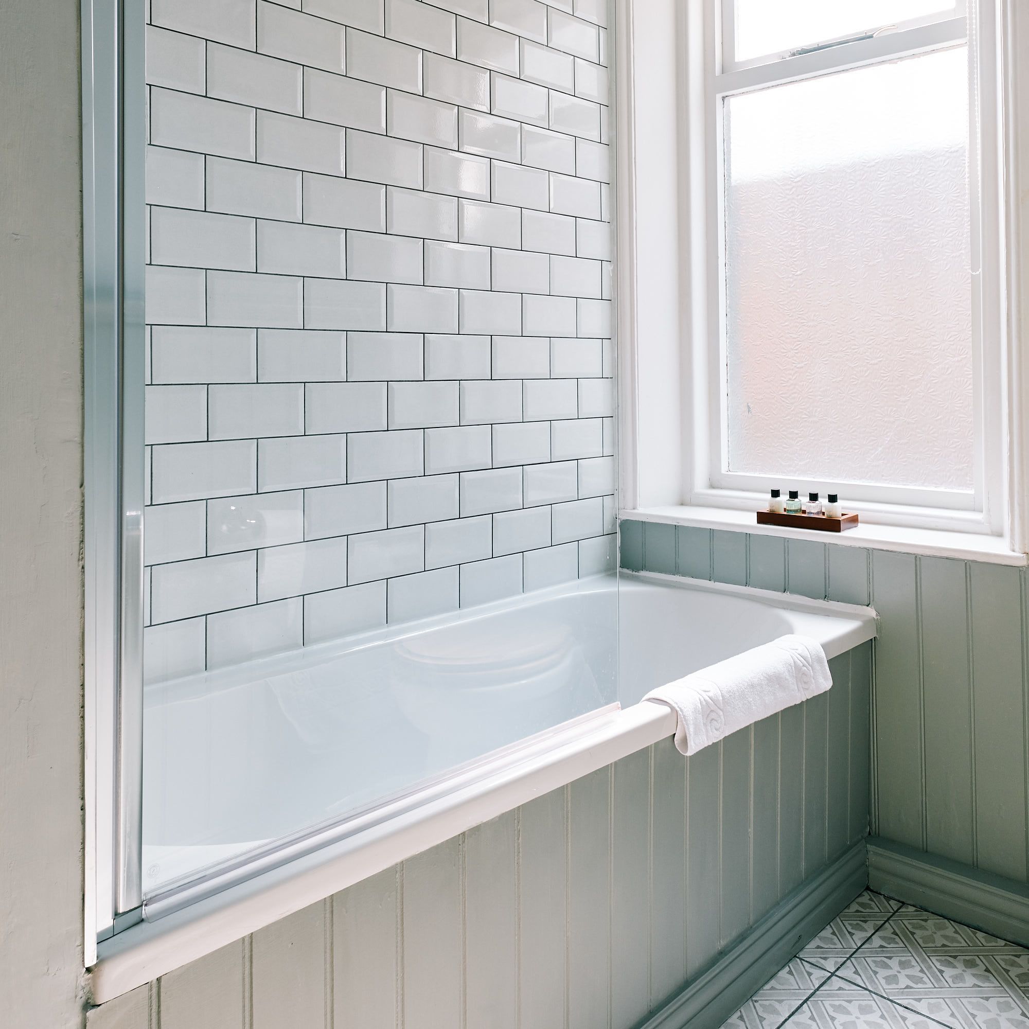 Un baño con una bañera blanca, una ventana con vistas y un revestimiento de azulejos.