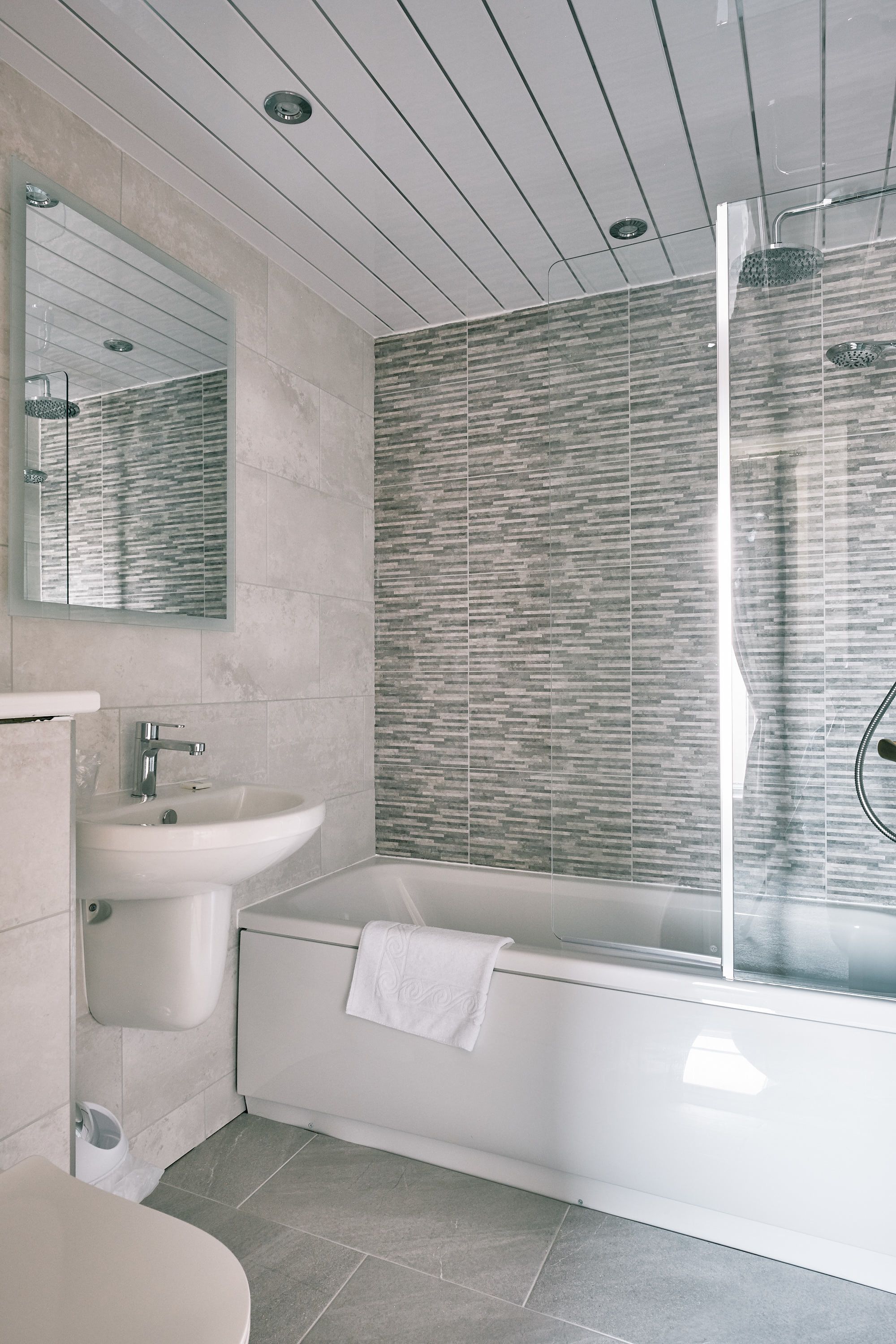 Un baño moderno con una bañera independiente, un lavabo y un espejo.