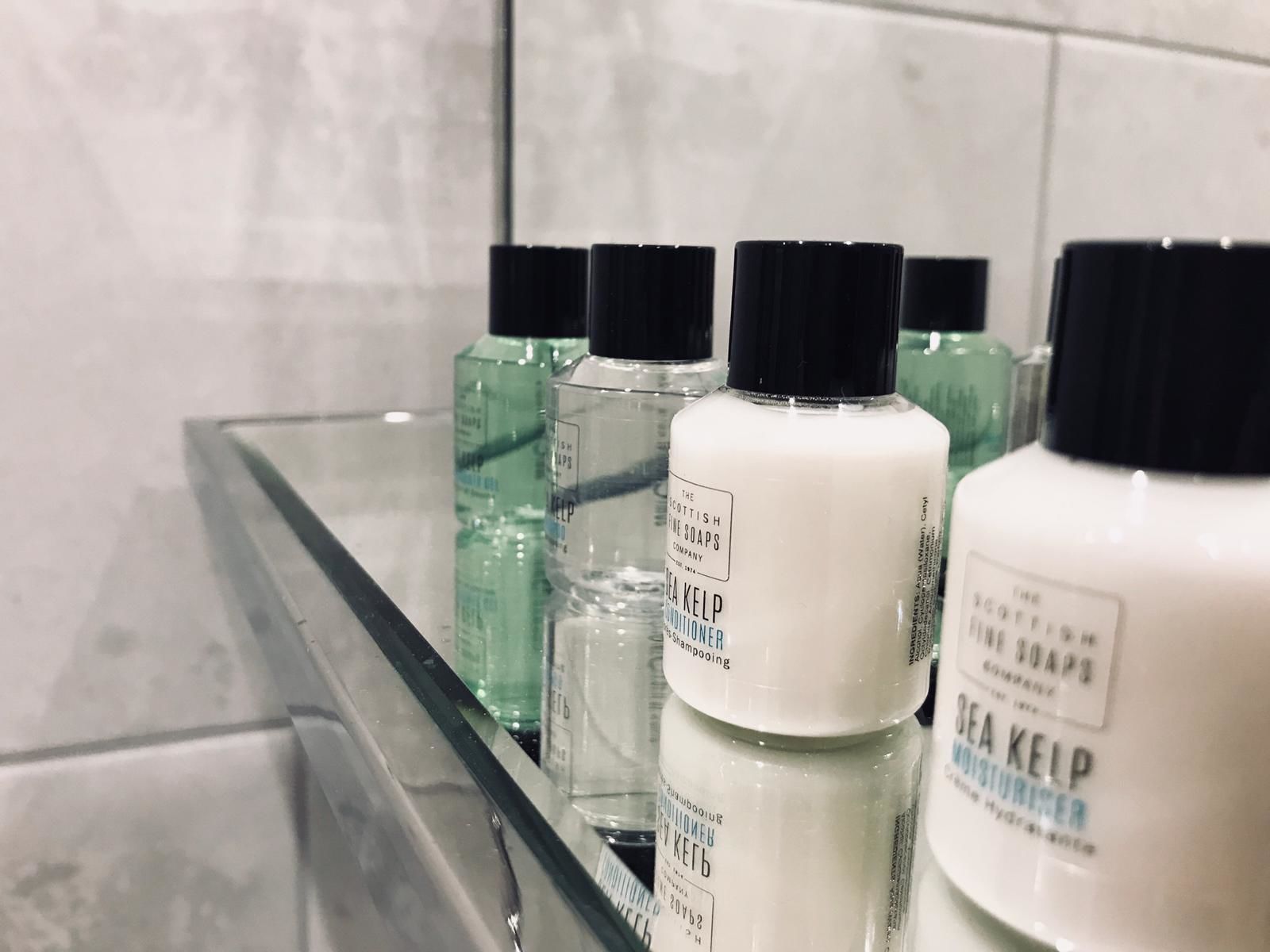 A bathroom shelf with multiple bottles of Sea Kelp Conditioner and other toiletries.