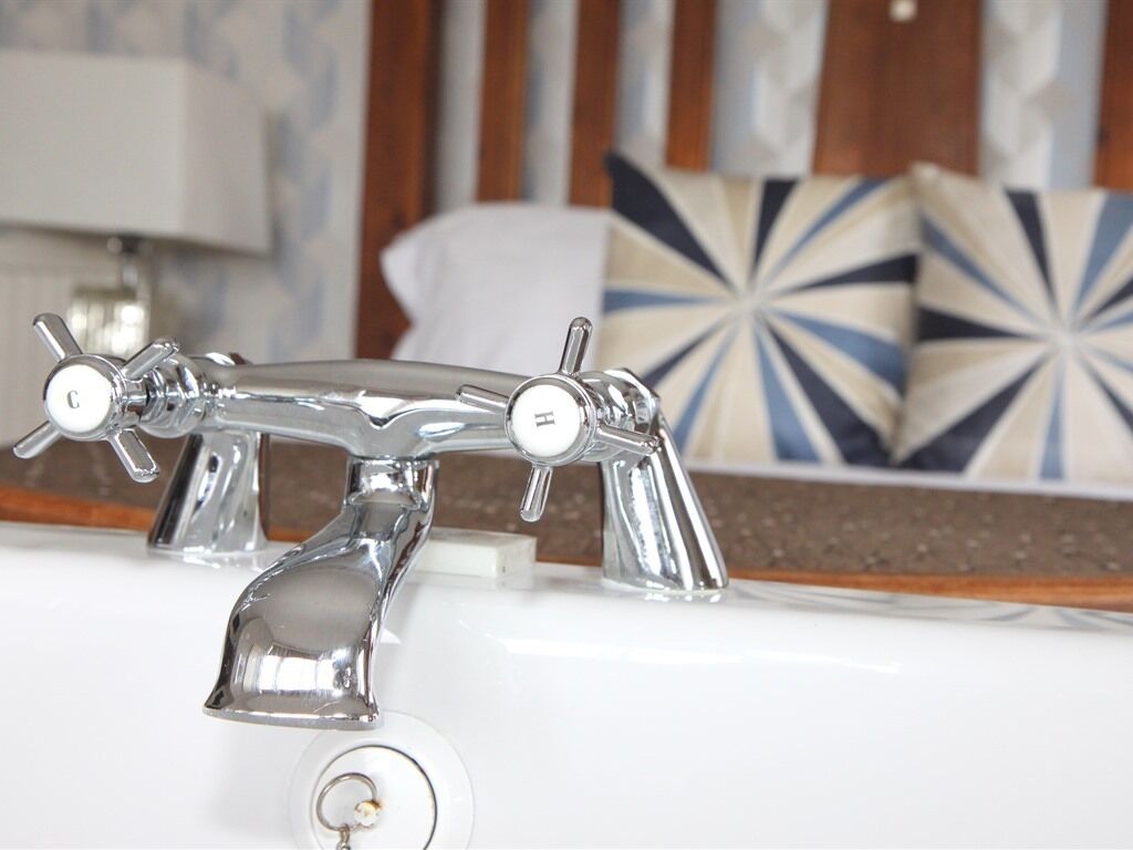 A bathroom with a chrome faucet and a towel rack.