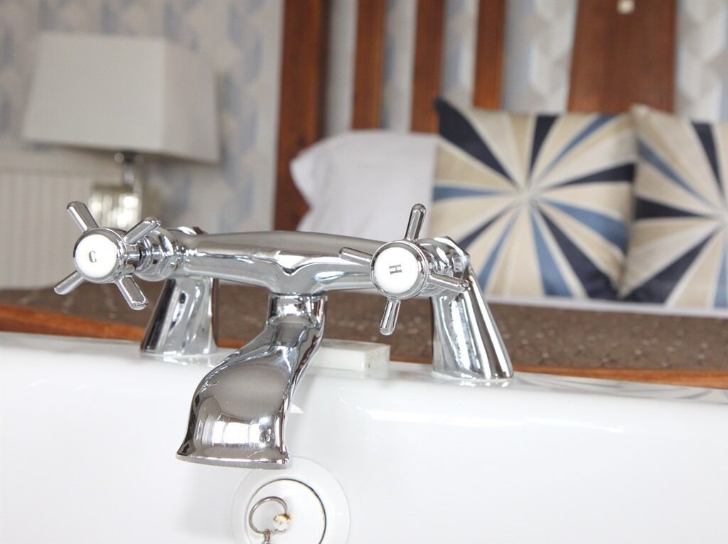Un baño con un grifo cromado, un perchero y una almohada decorativa al fondo.