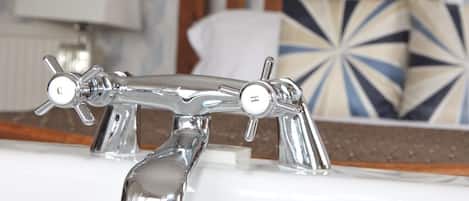Un baño con un grifo cromado, un perchero y una almohada decorativa al fondo.