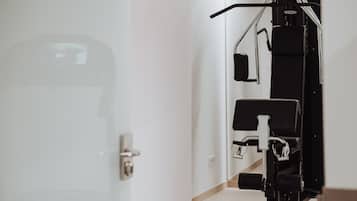 Un gimnasio con equipo de ejercicio, una puerta y un interruptor de luz en la pared.