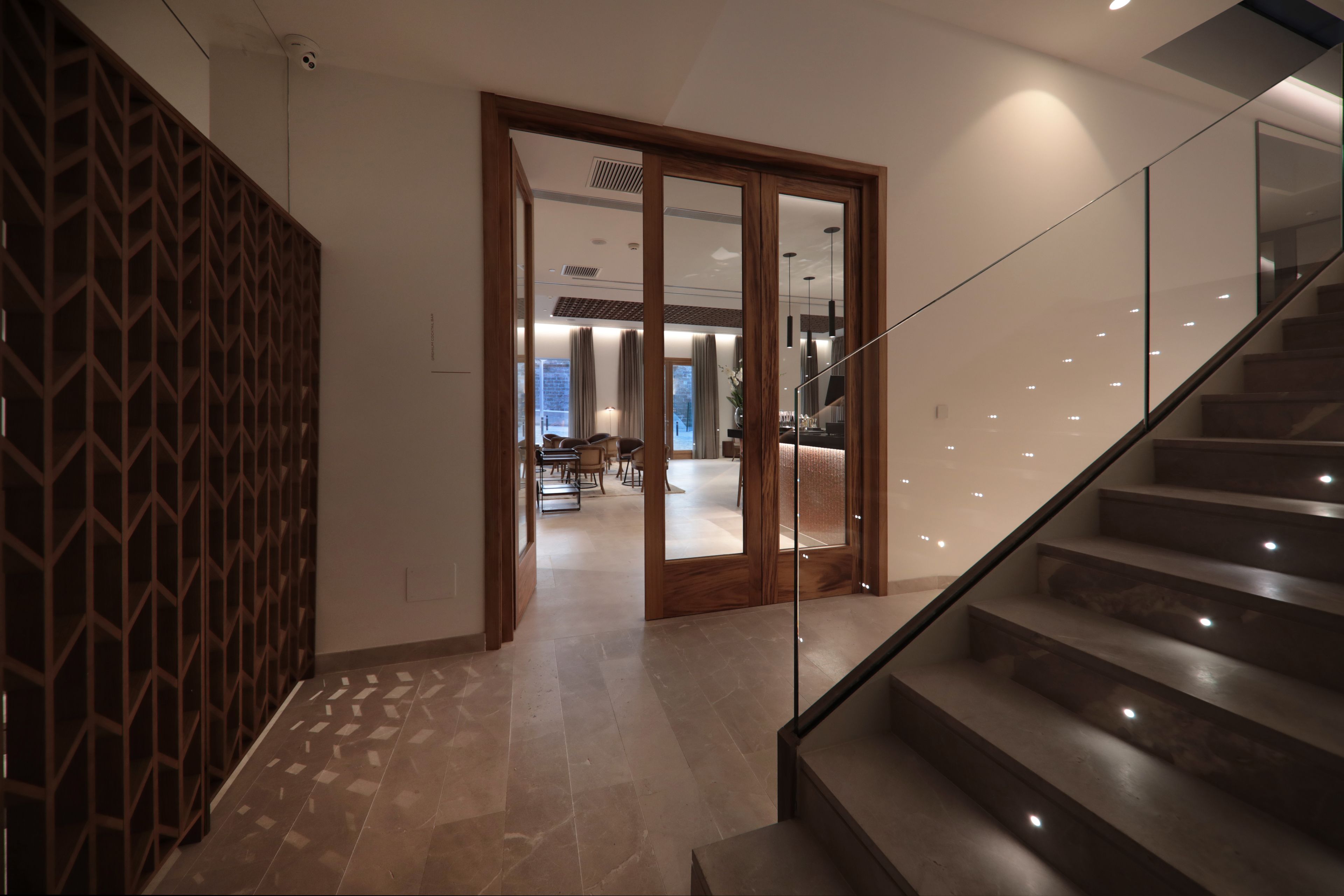 Un intérieur moderne avec un escalier, une cloison en bois et une vue sur un espace salle à manger.