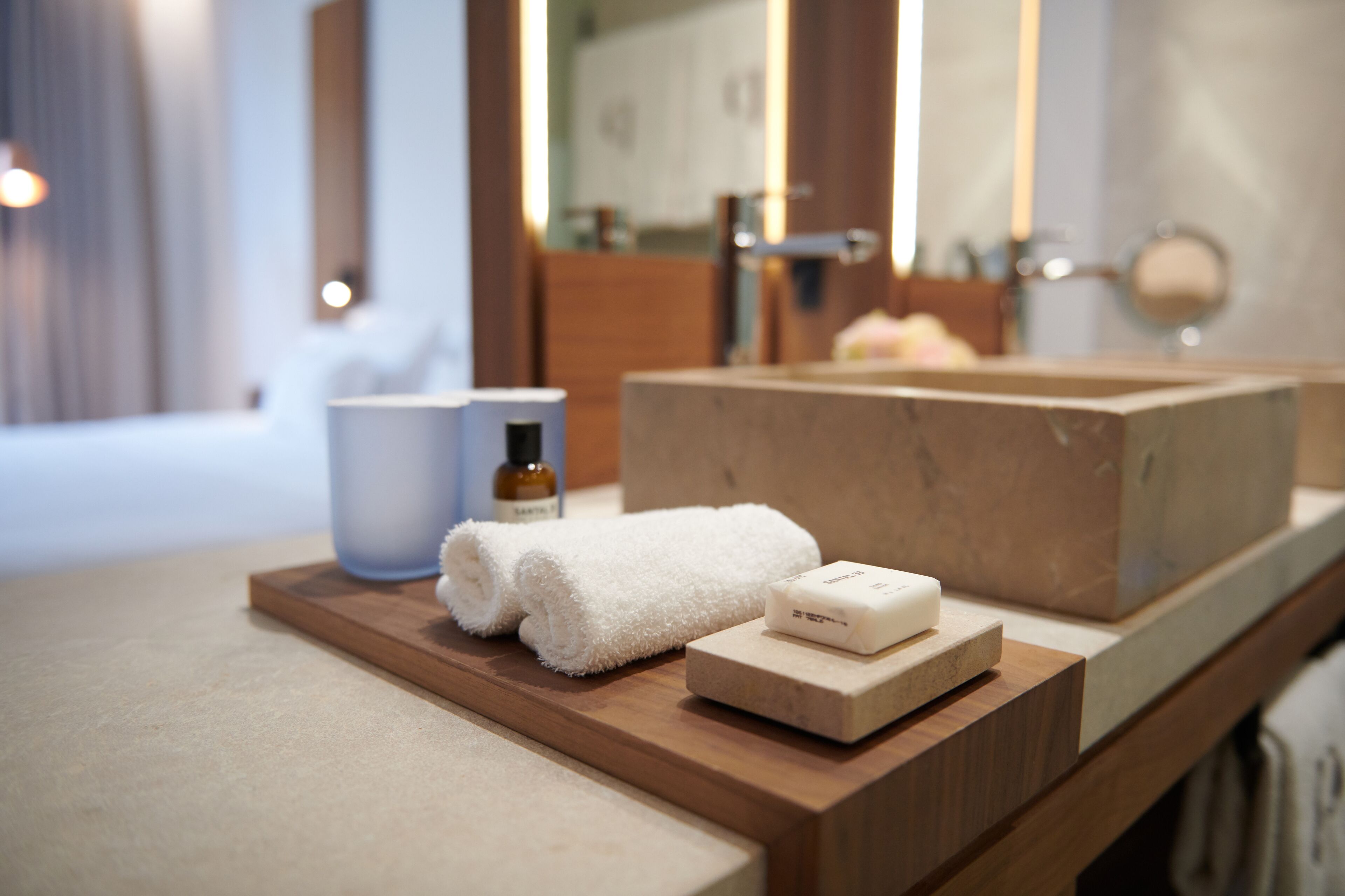 A bathroom vanity with a wooden countertop, a white towel, a soap bar, and a bottle of shampoo.