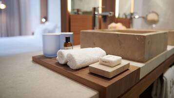 A bathroom vanity with a wooden countertop, a white towel, a soap bar, and a bottle of shampoo.