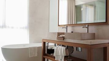 A modern bathroom with a freestanding bathtub, a wooden vanity with a large mirror, and a window with curtains.