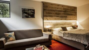 Quarto com cama, sofá, mesa de cabeceira e janela.