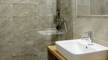 A modern bathroom with a glass shower enclosure, a white sink, and a wooden vanity.