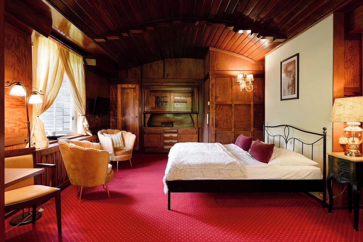 Ein gemütliches Zimmer mit Bett, Schreibtisch und Stuhl. Ein Schminktisch und eine Lampe sind an der Wand angebracht.