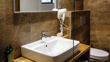 A modern bathroom with a large mirror, a white sink, and a hairdryer mounted on the wall.