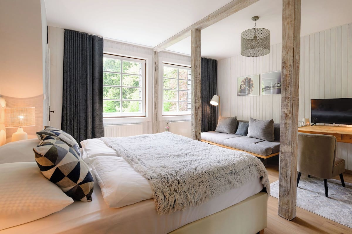 Ein Schlafzimmer mit einem großen Bett, einem Sofa, einem Schreibtisch und einem Fernseher.