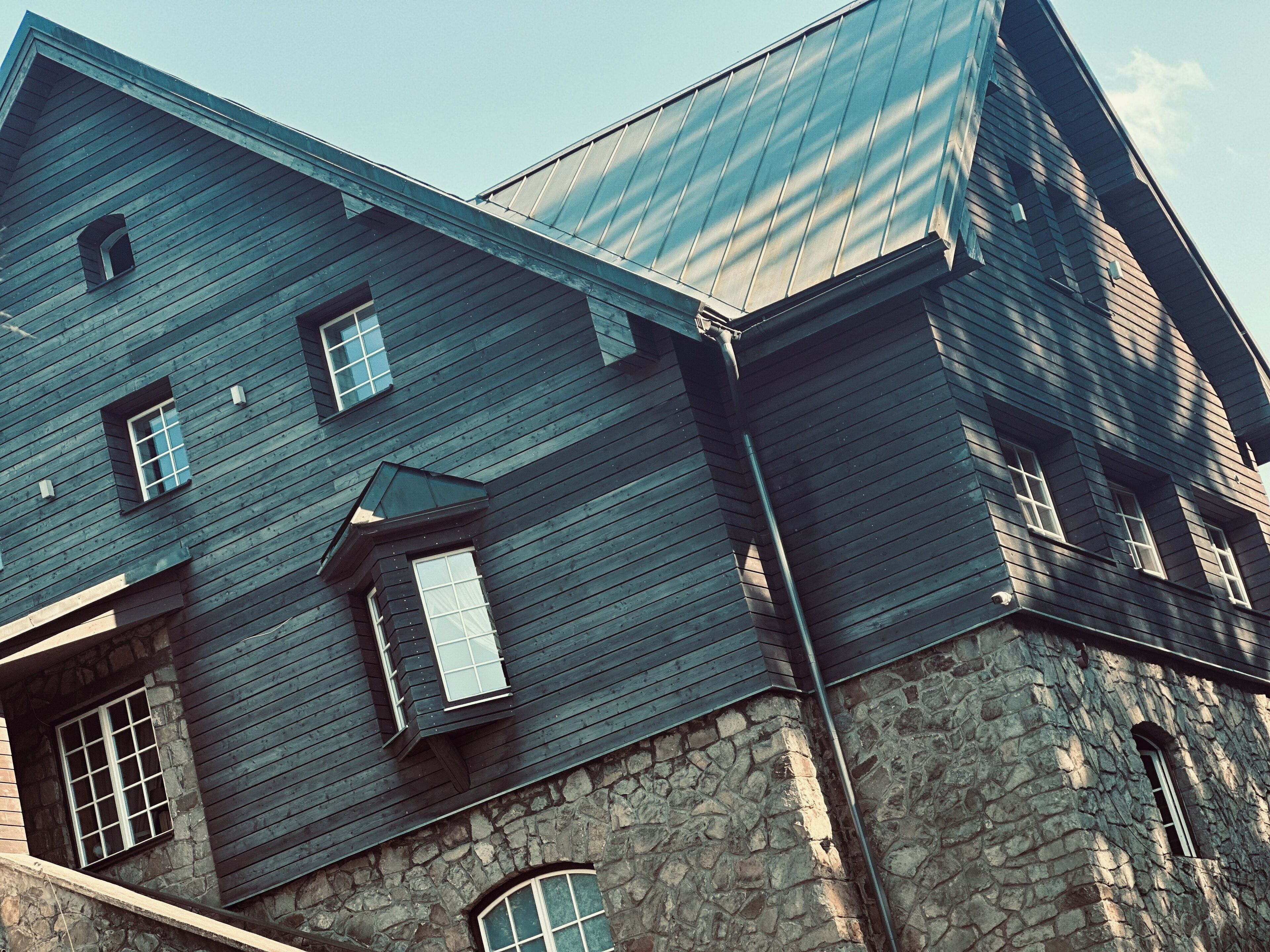 Un grand immeuble à étages, avec une base en pierre et un revêtement extérieur en bois foncé.