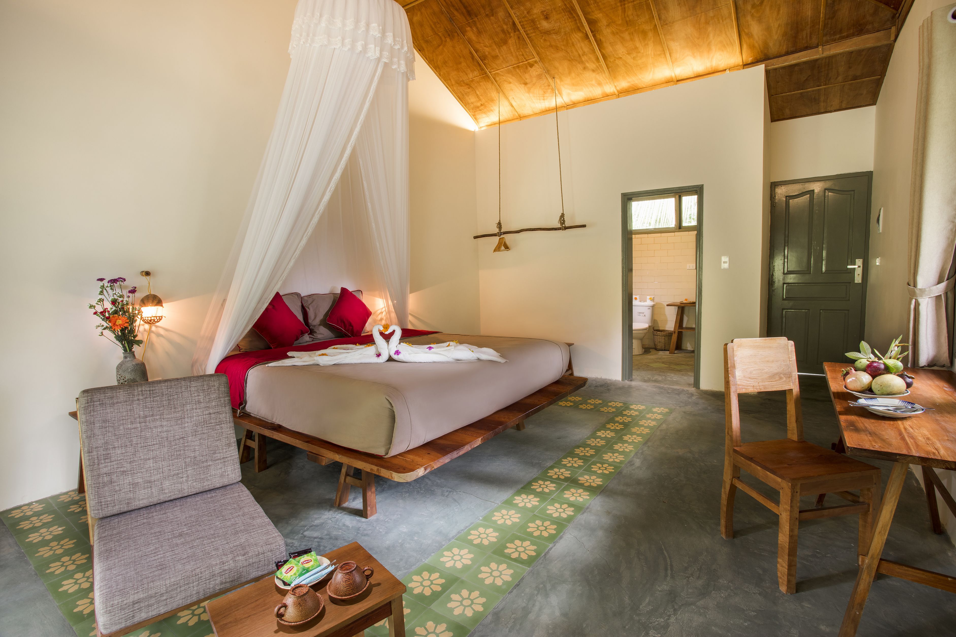 Een slaapkamer met een bed, een stoel, een tafel en een houten plafond.