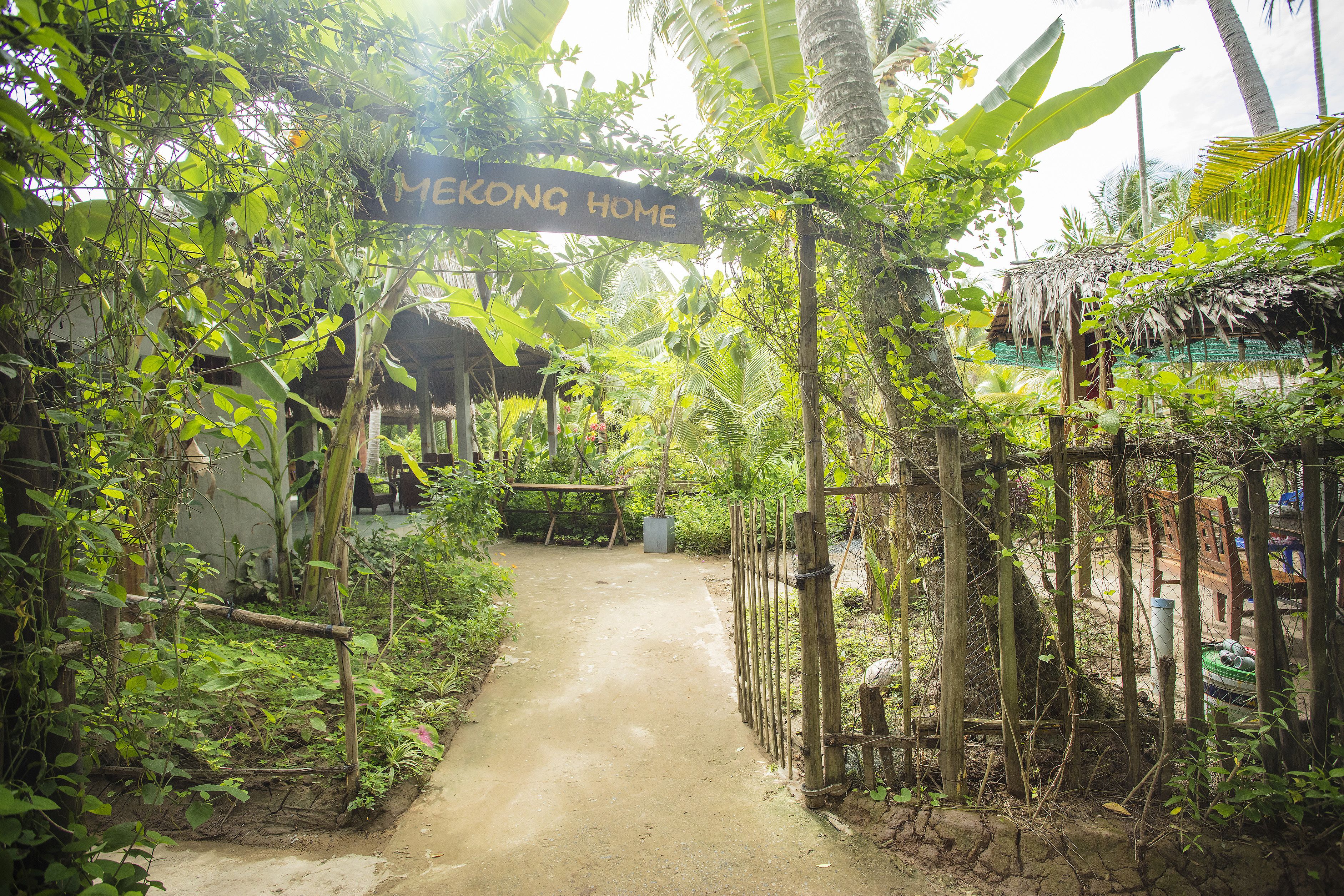 A pathway leading to a structure labeled "MEKONG HOME" surrounded by lush greenery and a thatched roof.