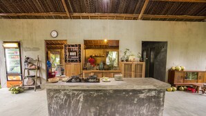 A rustic kitchen with a central island, wooden shelves, and a refrigerator. - Mekong Home (Phuoc Long)