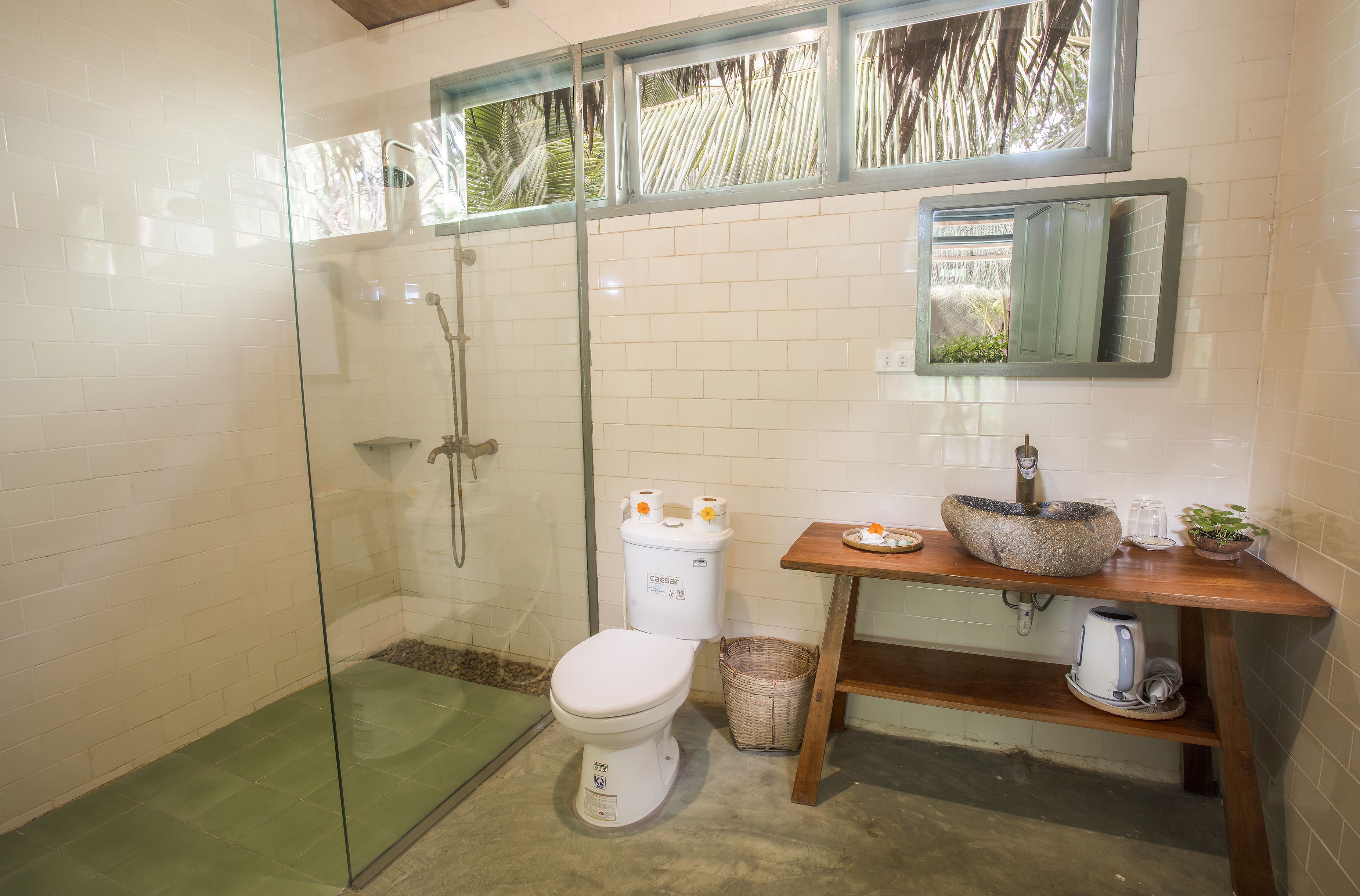 A bathroom with a glass-enclosed shower, a white toilet, a sink with a stone basin, and a mirror above the sink.