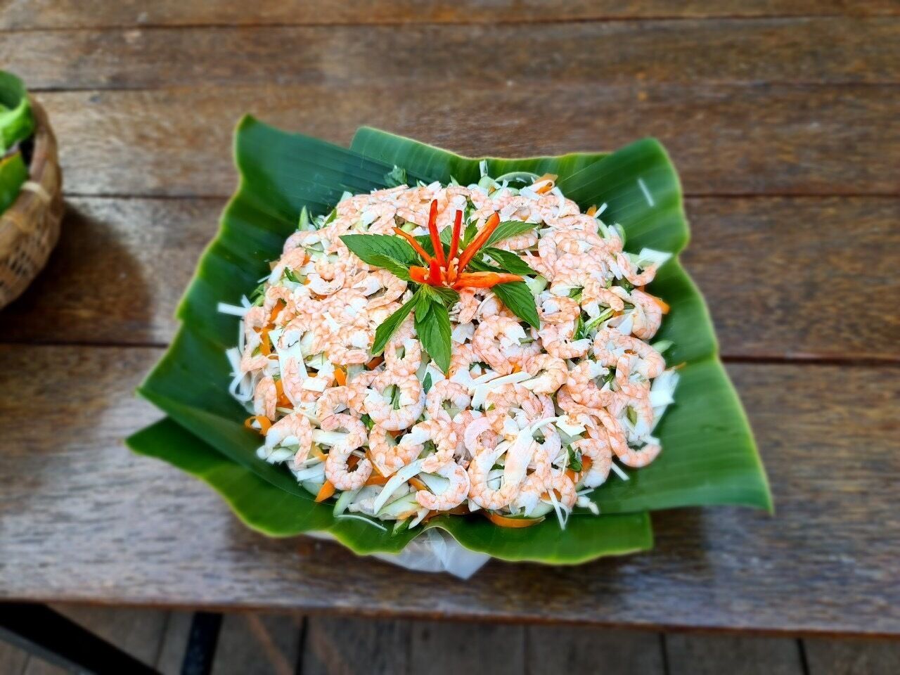 Une salade de crevettes servie sur une feuille de bananier.
