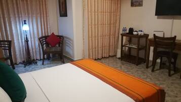 Habitación de hotel con cama, escritorio, silla, mesa y televisor.