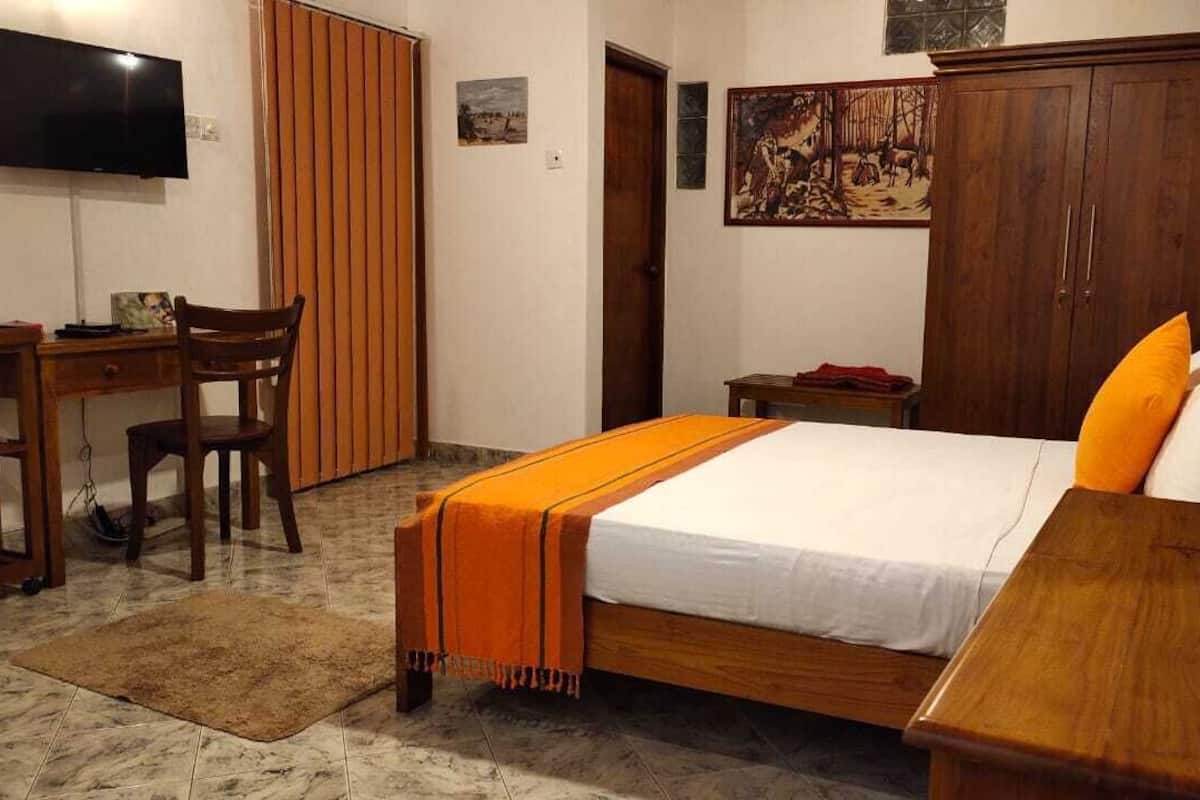 Un dormitorio con una cama, un escritorio, una silla, un televisor y un guardarropa.
