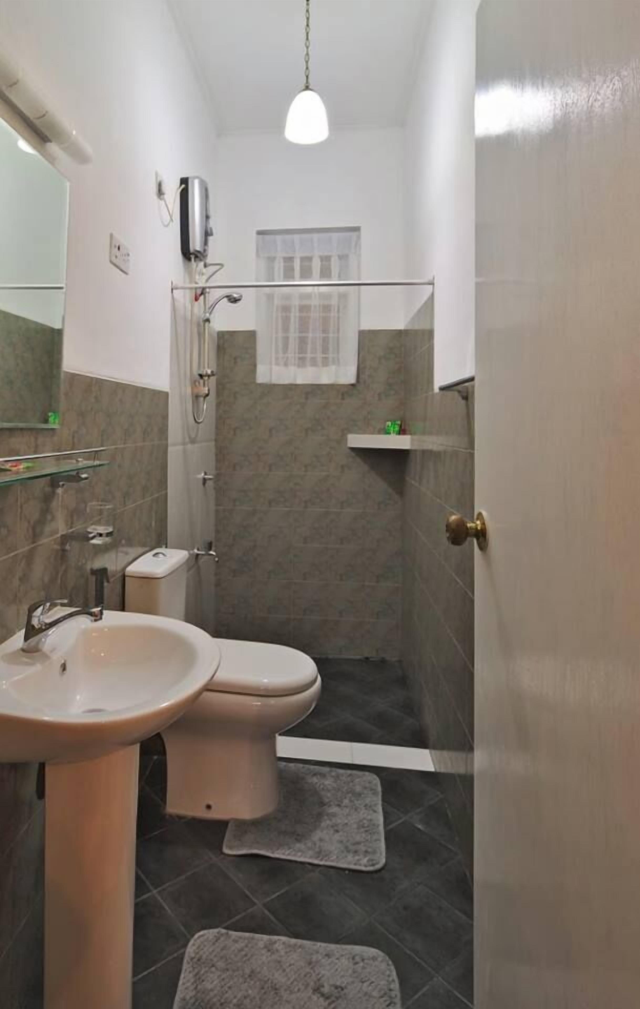 Ein kleines Badezimmer mit Waschbecken, Toilette und Duschbereich.