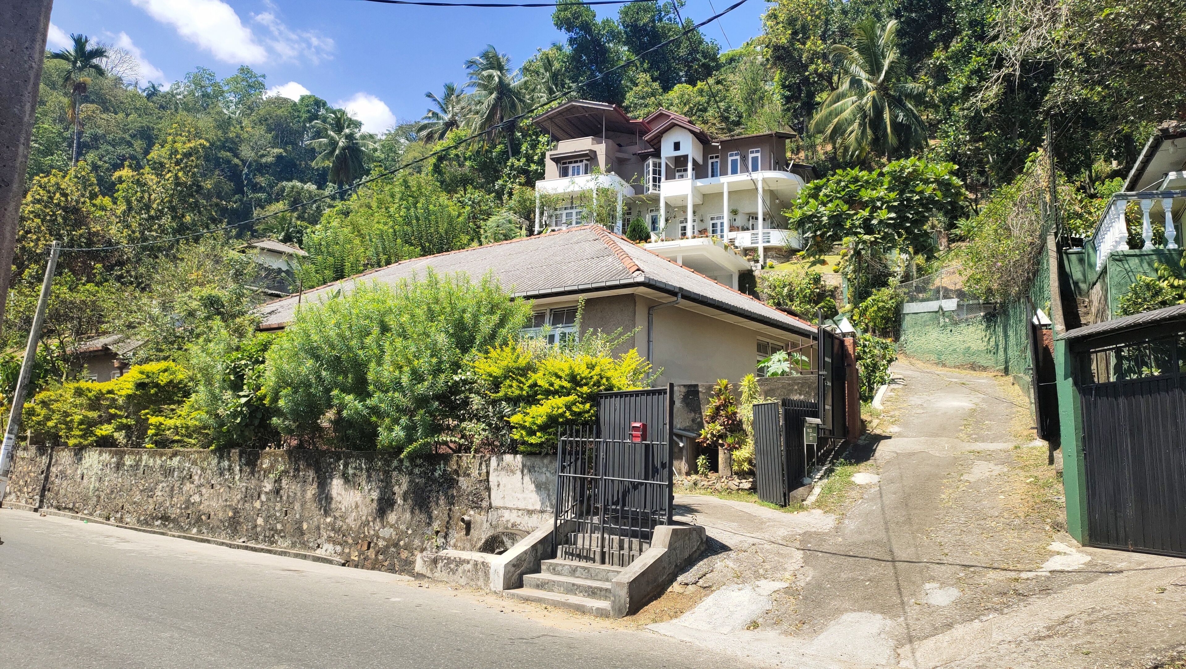 A residential house with a sloped roof, a gated entrance, and a staircase leading to the front door.