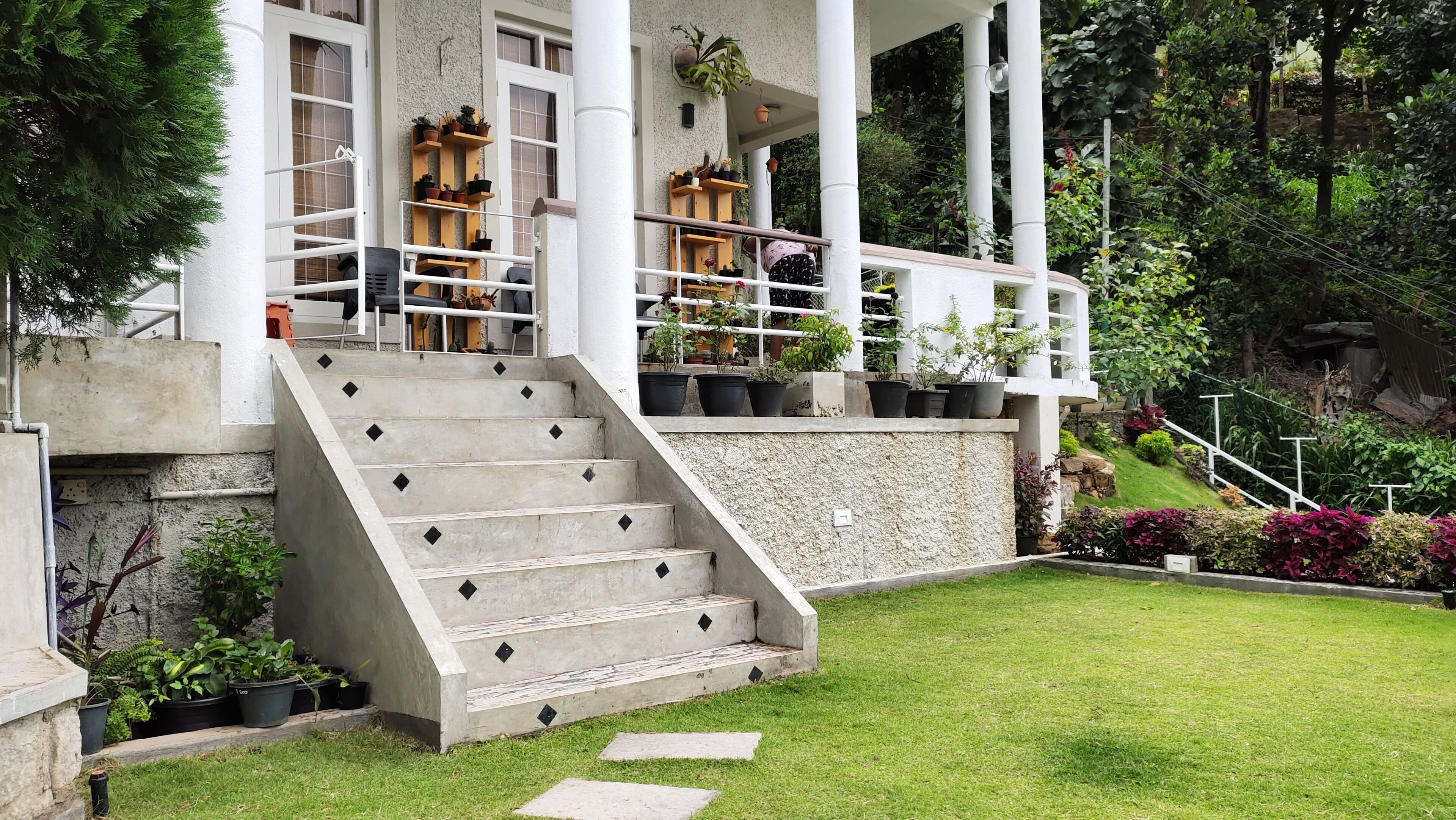 A modern building with a concrete staircase leading to a covered porch with potted plants.