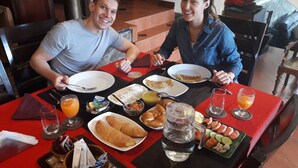Una mesa de comedor con platos de comida, vasos de jugo de naranja y una jarrón de agua.