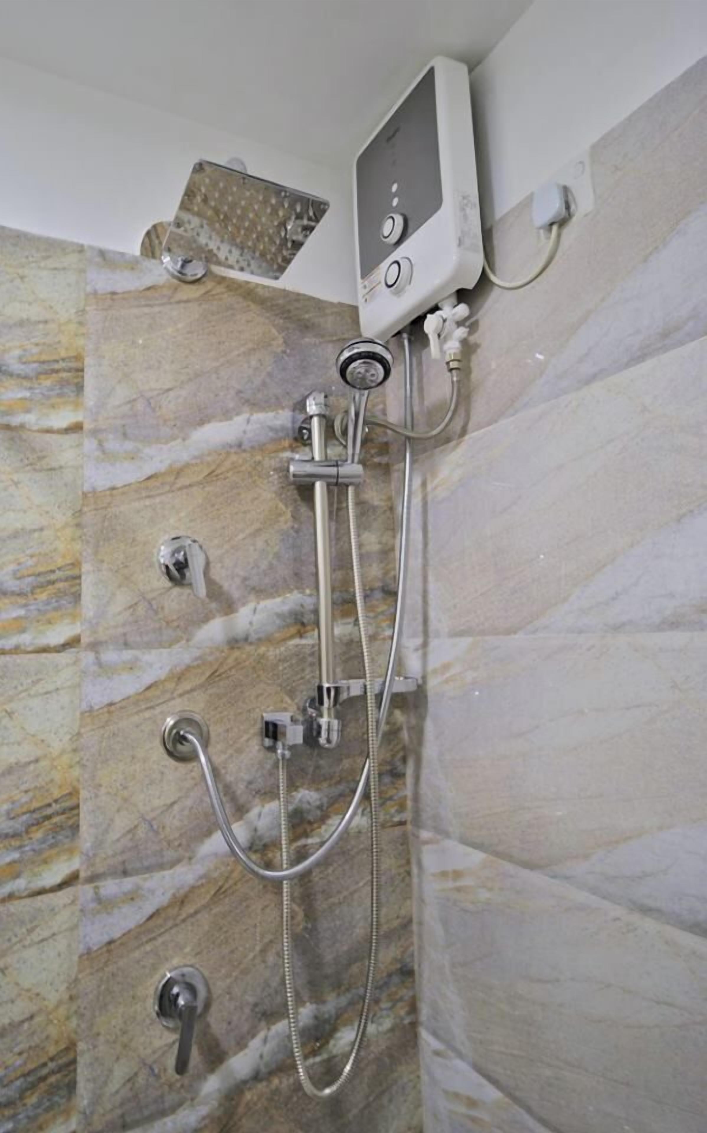 A shower with a handheld showerhead and a wall-mounted control panel.