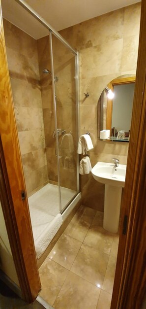 A bathroom with a glass-enclosed shower, a sink, and a mirror. - Hostal Moncloa (Madrid)