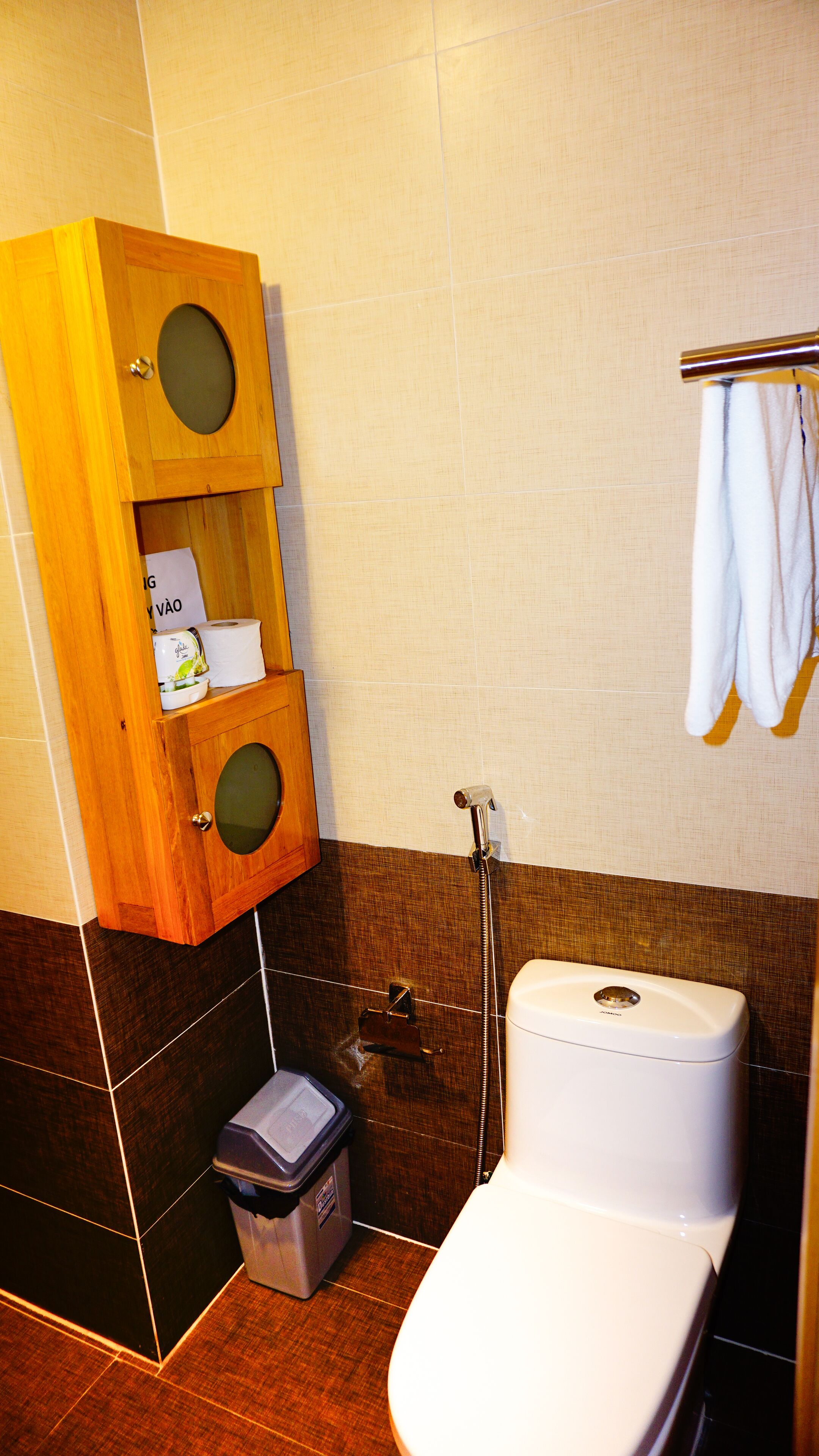 A bathroom with a wooden cabinet, a toilet, and a towel rack.