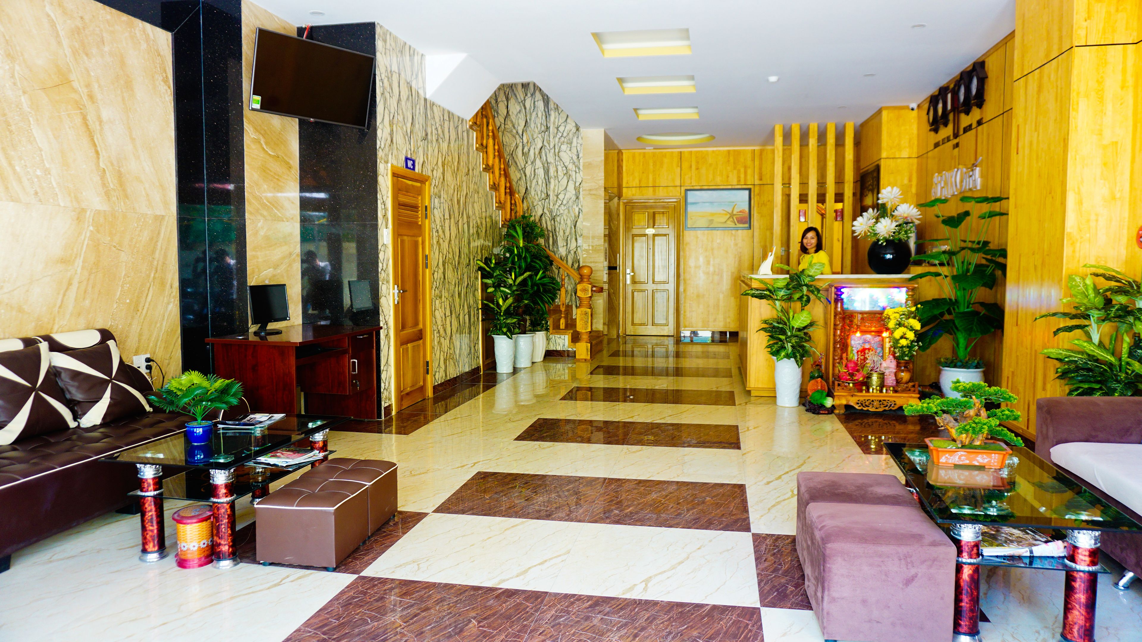 Un vestíbulo de hotel con mostrador de recepción, zona de estar y una escalera que conduce a los pisos superiores.