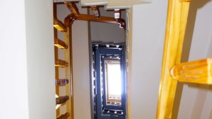 Una escalera con barandillas de madera y vista a una habitación con ventana y puerta.