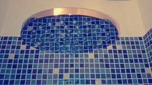 A bathroom with blue mosaic tiles and a circular sink with a metallic arch. - Beside the Vatican (Rome)
