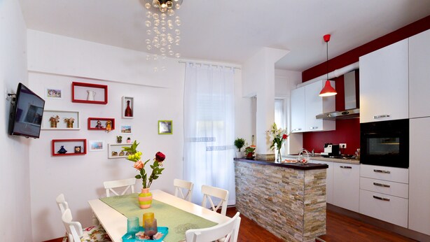 A modern kitchen with white cabinets, a red pendant light, and a stone island. - Beside the Vatican (Rome)