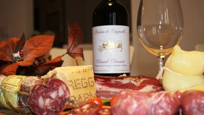 A selection of cheeses, cured meats, and a bottle of wine on a wooden board. - Beside the Vatican (Rome)