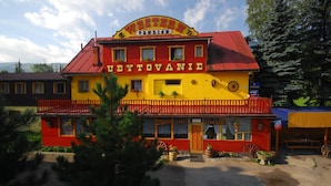 A Western-themed building with a red and yellow facade, a balcony, and a sign that reads "WESTERN PENZION UBYTOVANIE." - Penzión Western (Ruzomberok)