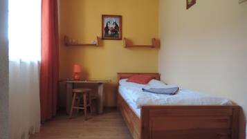 Una habitación pequeña y acogedora con una cama de madera, un escritorio con silla y una mesita.