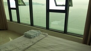 Een hotelkamer met een bed, een raam met uitzicht op zee en een handdoek op het bed.
