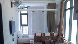 Een hotelkamer met een bed, bureau, stoel, televisie en raam met gordijnen.