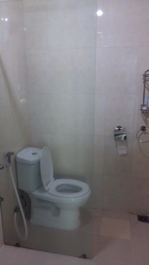 A bathroom with a toilet, a hand dryer, and a towel dispenser.