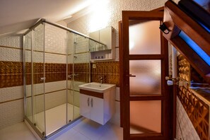 Baño con cabina de ducha de vidrio, lavamanos y mueble.